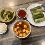 Collage of three tofu dishes: breakfast soup with zucchini, fresh spring rolls with herbs, and savory tomato tofu over rice