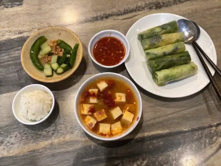 Collage of three tofu dishes: breakfast soup with zucchini, fresh spring rolls with herbs, and savory tomato tofu over rice
